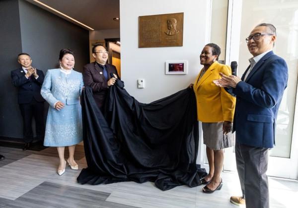 A group of people unveiling a bronze plaque on a wall.